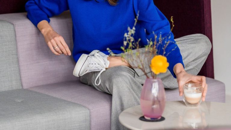 Bildauschnitt, wo Rebecca auf dem Sofa sitzt und die Kaffeetasse abstellt. Symbolisch für Business Coaching zur Verlinkung auf diese Unterseite.